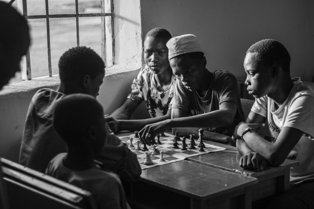 Children gathering around a chess board, analyzing moves together